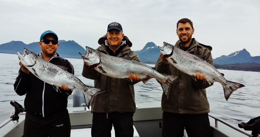3 men holding their Alaskan caught salmon.